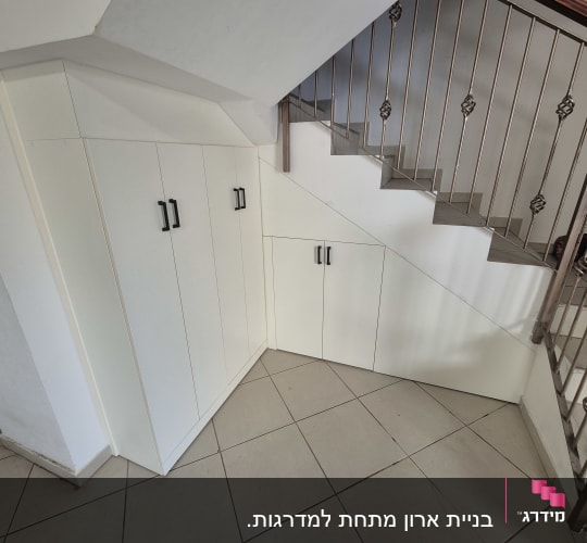 ארון לבן מתחת למדרגות עם ידיות שחורות